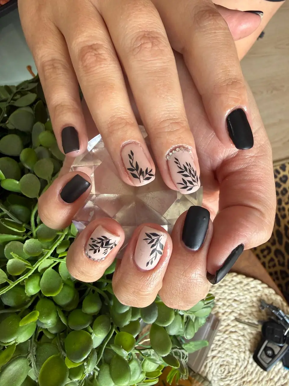 Matte black and nude nails with botanical leaf art